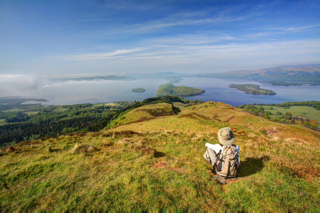 A person sits atop Conic Hill by Loch Lomond.